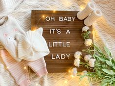 a wooden sign that says oh baby it's a little lady next to flowers