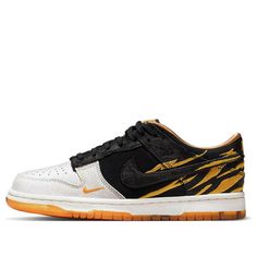 Introducing the Nike Dunk Low GS "God of Wealth"! This special release is made exclusively for big kids, in celebration of the Lunar New Year. Featuring an eye-catching combination of grey and black suede, with amber stripes embroidered throughout the rear upper, this shoe is sure to turn heads. The black finish on the eyestay, Swoosh, and heel overlay provides a nice contrast, while the gold satin lining adds a touch of luxury. The low-top design is mounted on a rubber cupsole that pairs white sidewalls with an orange translucent outsole marked with black tiger stripes. Don't miss your chance to get your hands on this limited edition release! (SNKR/Retro/Skate/Casual/Low Top) God Of Wealth, Black Tiger, Black Tigers, Year Of The Tiger, Gold Satin, Tiger Stripes, Lunar New Year, Nike Dunk Low, Top Design