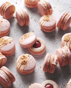 pink macaroons with white icing and raspberry fillings on a baking sheet