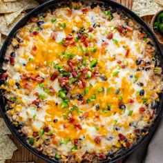 an overhead view of a mexican dip in a skillet with tortilla chips on the side