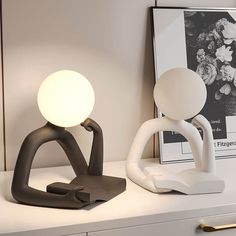 a white table lamp sitting on top of a desk next to a black and white sculpture