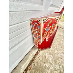 a red and gold vase sitting on the side of a white wall next to a door