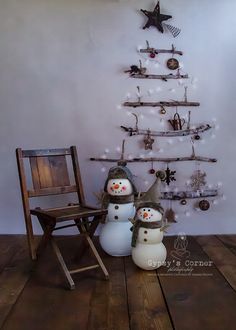 two snowmen are standing next to a small christmas tree with ornaments on the branches