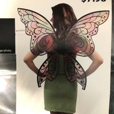 a woman in a green dress with a butterfly wings on it's back is standing