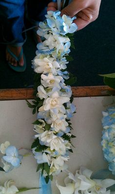 a person cutting flowers with scissors on a table in front of some blue and white flowers