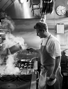 a man cooking in a kitchen with steam coming out of the burners and on the stove