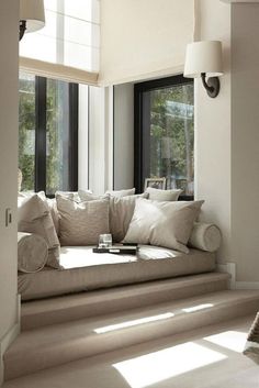 a living room filled with lots of furniture next to large windows on the side of a wall