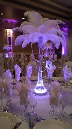 the table is set with white linens, silverware and crystal vases for centerpieces