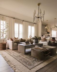 a living room filled with lots of furniture next to a window covered in white curtains