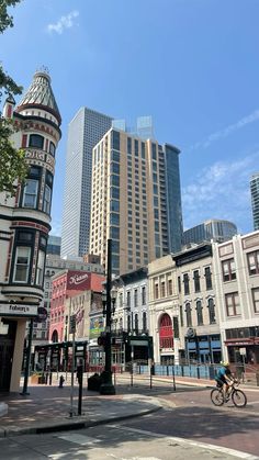 a man riding a bike down a street next to tall buildings in the city center