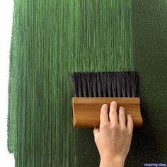 a person using a brush to paint a wall with green grass on the outside and inside