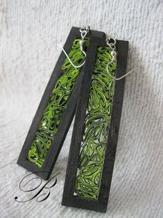 two wooden earrings with green and black designs on them