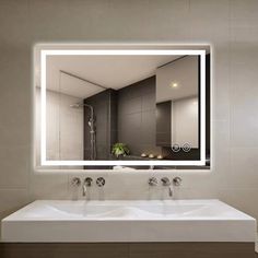 a bathroom sink with a large mirror above it and lights on the wall behind it