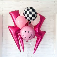 some balloons are in the shape of stars and a smiley face with a checkerboard ballon on top