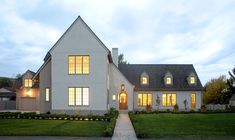 a large white house with lots of windows and grass in the front yard at dusk