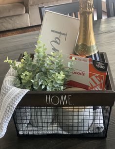 a basket filled with books and flowers on top of a table next to a bottle of champagne