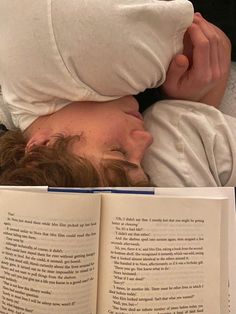 a person laying in bed with an open book over their head and reading it to someone else