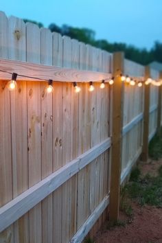 some lights are hanging on the side of a fence