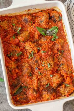 a casserole dish with meatballs and tomato sauce in it on a table