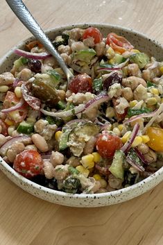 a salad in a bowl on a wooden table with a spoon sticking out of it