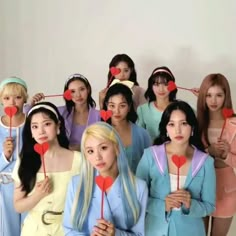 a group of women standing next to each other holding heart shaped lollipops