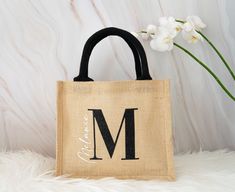 a burlock bag with the letter m on it and a flower in front