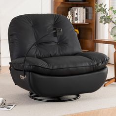 a black leather recliner chair sitting on top of a wooden floor next to a book shelf