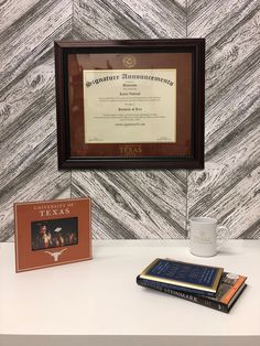 there is a plaque and two books on the table next to each other in front of a wall