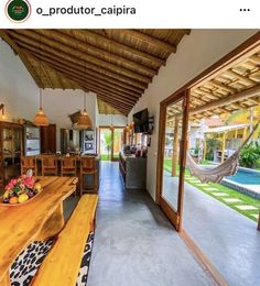 the inside of a house with wooden tables and hammocks hanging from the ceiling