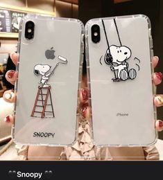 someone holding up their phone case with snoopy on it and an apple in the background