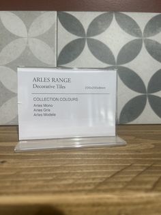 a business card holder on top of a wooden table in front of tile wallpaper