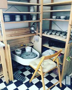 a chair sitting in front of shelves filled with pots and pans on top of a checkered floor