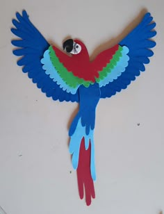 a colorful bird made out of paper on top of a white surface with an eye in it's beak