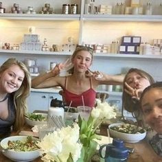 four women sitting at a table with bowls of food in front of them