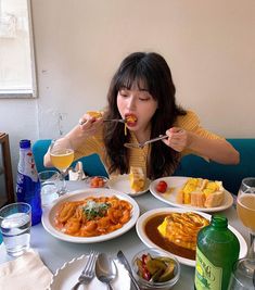 a woman sitting at a table with plates of food and drinks in front of her