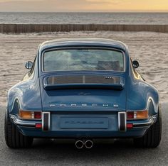 an old blue porsche parked on the beach