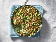 a pan filled with meat and vegetables on top of a blue cloth next to a spoon