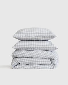 three pillows stacked on top of each other in grey and white checkered linens