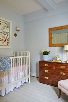 a baby's room with a crib, dresser and mirror on the wall