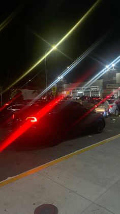 cars parked in a parking lot at night with bright lights shining on the car's hoods