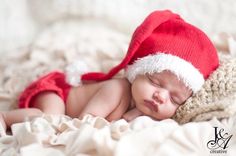 a baby wearing a santa hat sleeping on a blanket