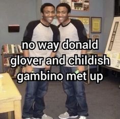 two young men standing next to each other in front of a desk and bookshelf