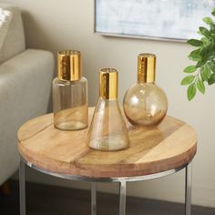 three glass vases sitting on top of a wooden table next to a white couch