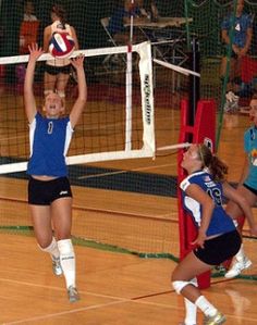 two girls are playing volleyball on the court