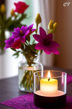 a lit candle sitting on top of a table next to a vase filled with flowers