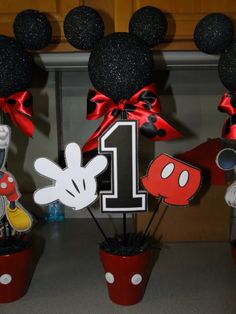 mickey mouse centerpieces are decorated with red bows and black paper decorations for the first birthday party