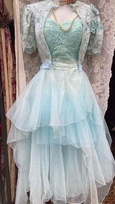 a mannequin wearing a blue dress in front of some laces and fabric