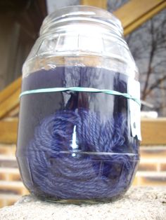 a glass jar filled with yarn sitting on top of a cement slab next to stairs