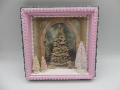 a small pink frame with a christmas tree in the center and snow on the ground