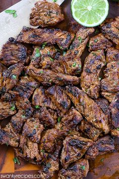 grilled steaks with lime and parsley on a cutting board next to a knife